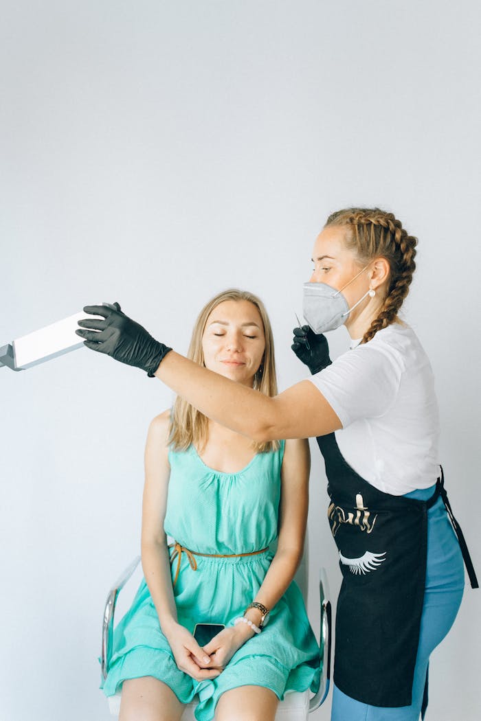 A beauty professional applying cosmetic treatment to a woman in a salon setting.